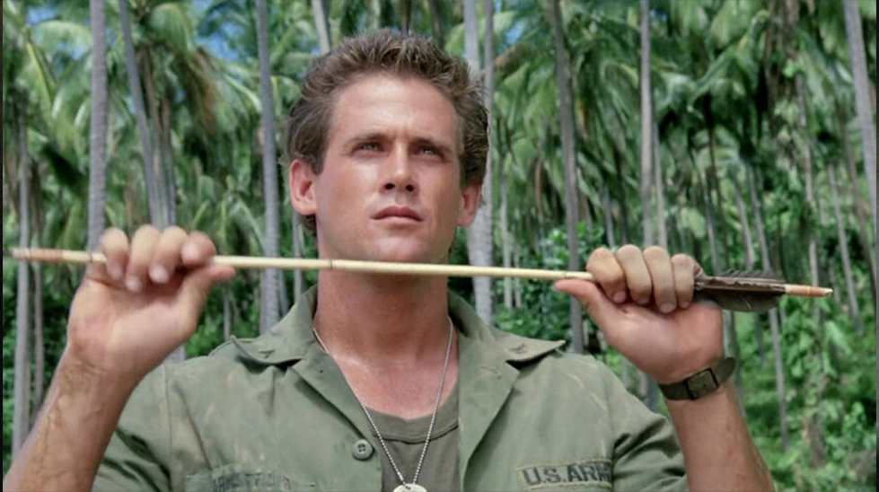 Michael Dudikoff as Joe Armstrong holding an arrow in the jungle, American Ninja (1985).