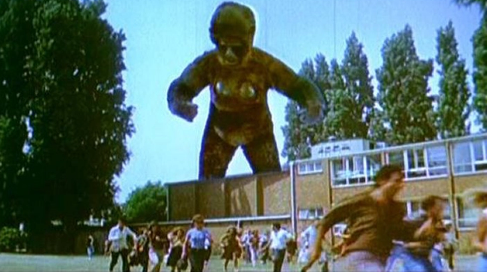 Queen Kong (1976) filminden dev dişi maymunun insanları kovaladığı sahne