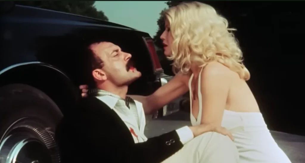 Kırmızı Kelebek (1982) filminde Frances Chandler ve yaralı aktör, araba yanında dramatik aksiyon sahnesi.