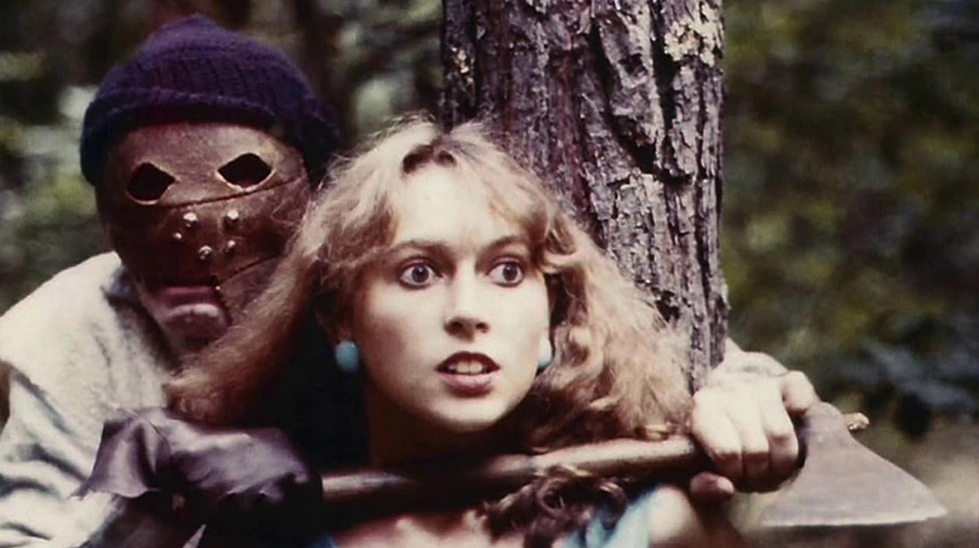 Mad Mutilator (Ogroff) filminden, maskeli katilin ormanda genç bir kadını baltayla rehin aldığı gerilim dolu sahne.