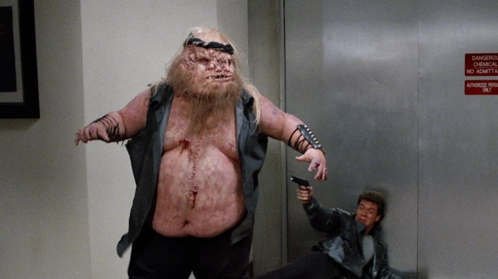 Dead Heat (1988) filminden devasa mutant zombi karakteri ile polis memuru arasında geçen şiddet dolu çizgi film vari çatışma sahnesi.
