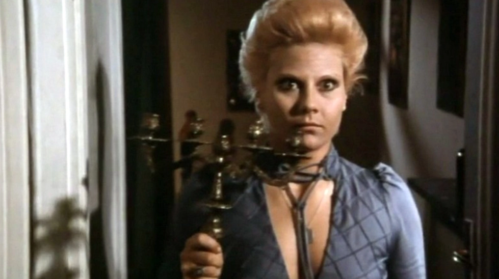 Renato Polselli'nin Mania (1974) filminden, elinde şamdan tutan kadın karakterin karanlık bir koridorda dehşet içinde baktığı gotik korku sahnesi.